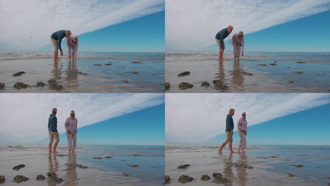 成熟的夫妇一起沿着空旷的海滩散步