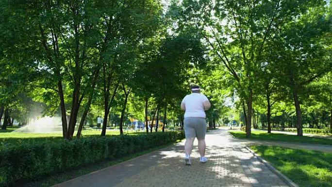 肥胖男子在公园慢跑，与超重作斗争，每天进行艰苦的锻炼