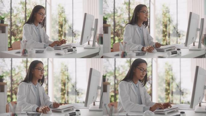 年轻的女医生穿着白大褂，在办公室里用个人电脑工作。美丽的亚洲医疗保健专业人员，负责测试结果，患者治疗