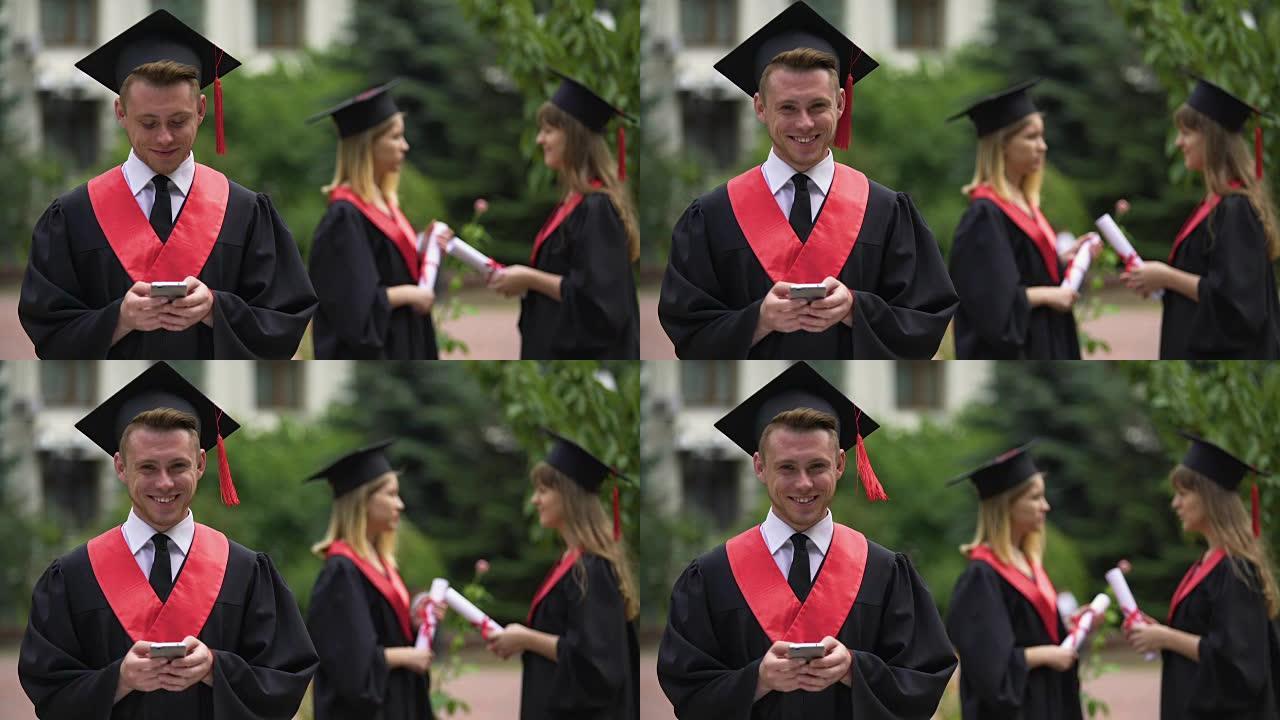 男毕业生在手机上打字留言，微笑对着镜头，毕业