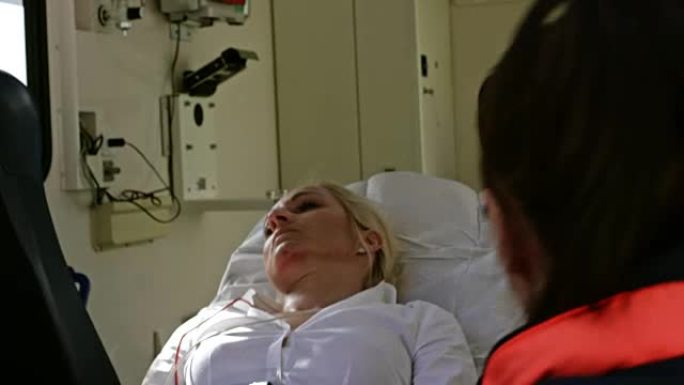 受伤的白人妇女躺在担架上被装载到救护车上