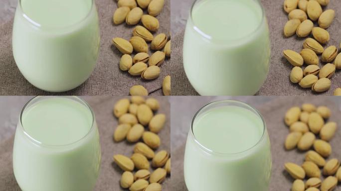 开心果牛奶在玻璃和开心果在灰色背景。纯素食植物牛奶。向上倾斜