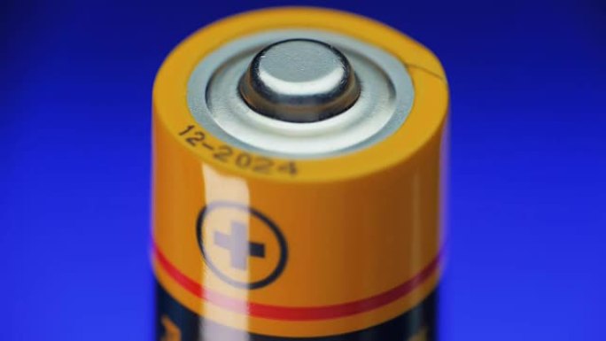 碱性电池在蓝色背景上旋转。加号是特写