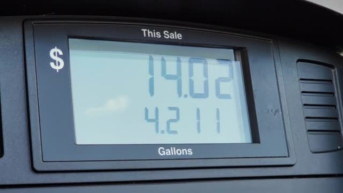 加油站的一个汽油泵的特写镜头显示，为泵送的加仑燃料支付了美元。屏幕显示加满汽车油箱的总成本。高油价