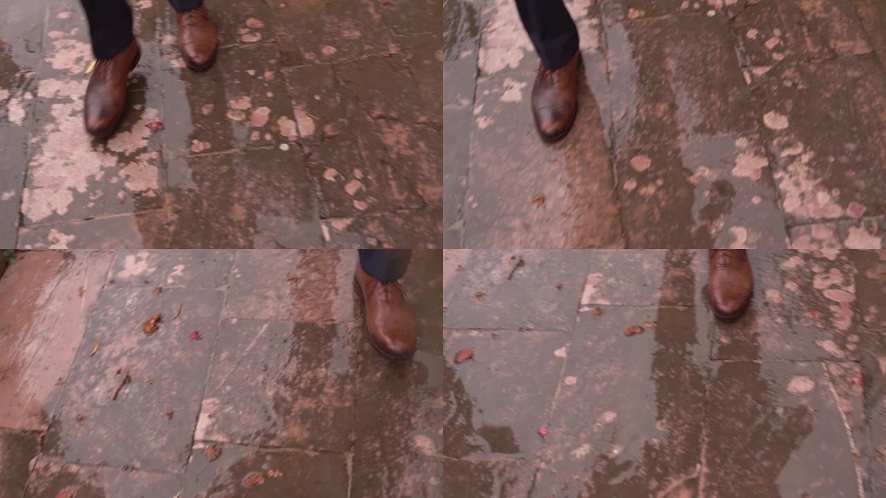 穿着西装的男人在雨中走在湿瓷砖上。裁剪