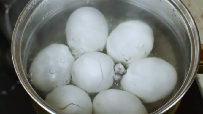 装有沸水的铁锅，煮沸白色鸡蛋。水在锅中煮沸，煮沸鸡蛋。在煤气炉上煮鸡蛋的过程。厨师准备鸡蛋。放大特写