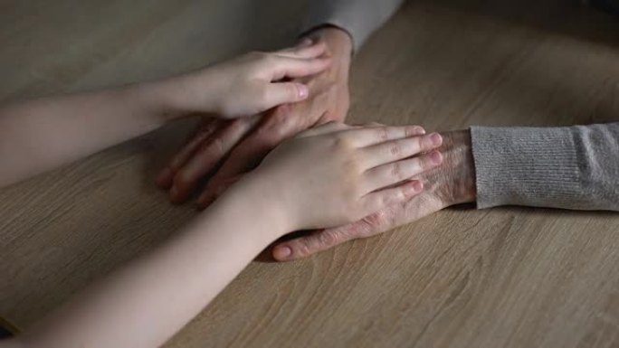 小女孩抚摸祖母的手，亲戚支持，家庭世代相传
