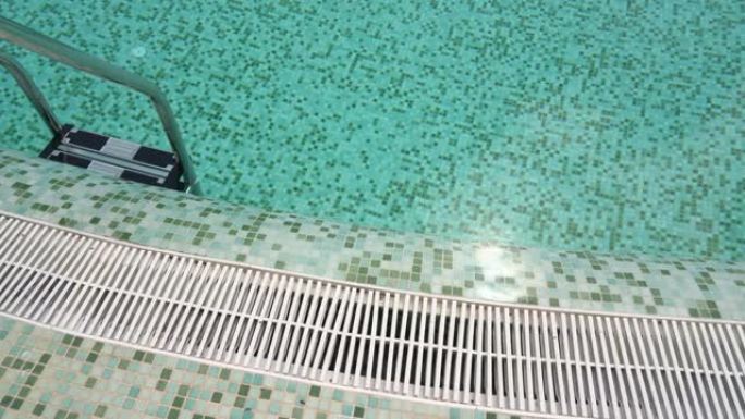 由钢栏杆制成的楼梯进入酒店别墅的游泳池的蓝色水。慢动作。
