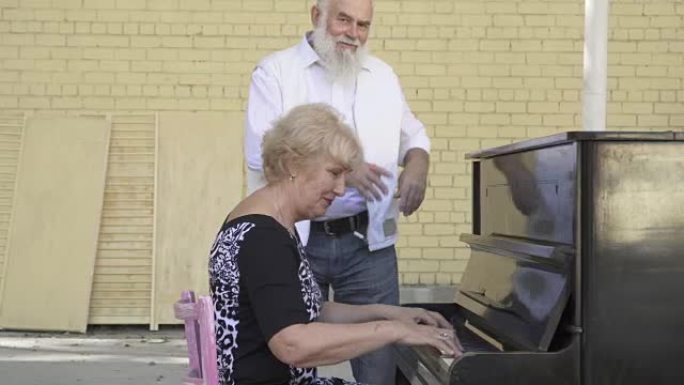 老胡子男人在妻子弹钢琴时跳舞