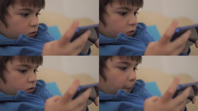 特写镜头孩子在家沙发上玩手机游戏。男孩在手机上玩电子游戏。学龄前儿童在沙发上玩电子游戏智能手机。儿童