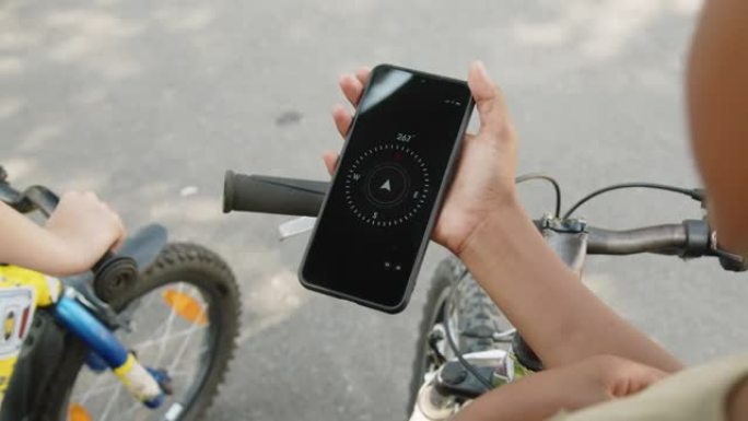 使用智能手机上的指南针骑自行车的不同孩子的手
