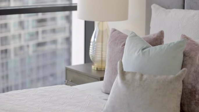 现代公寓中的时尚卧室，舒适的床上有柔软的靠垫和枕头。
