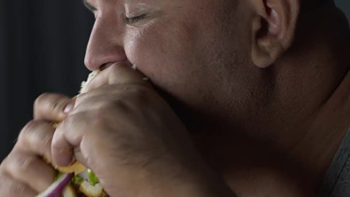 超重的男人用油性三明治馅，享受垃圾食品，慢动作