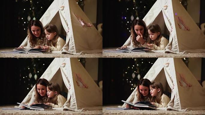 妈妈正在读一个女儿的故事，那晚和她躺在房子的帐篷里。女孩在微笑