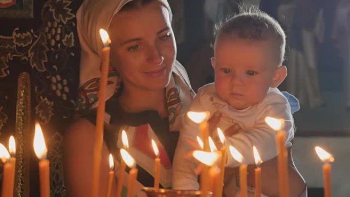 母亲和小儿子在教堂里观察燃烧的蜡烛