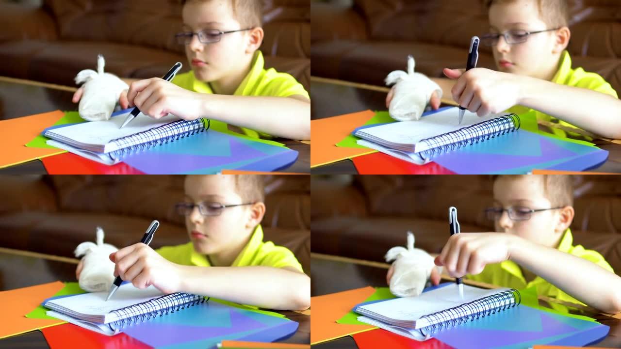 戴眼镜和断手的男孩试图用左手做作业