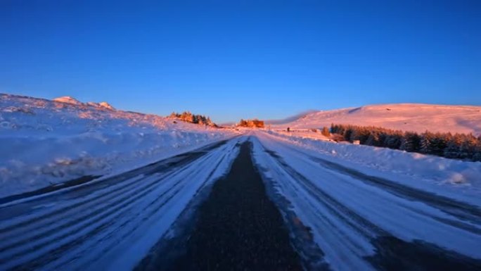 黄昏时在雪山路上行驶。