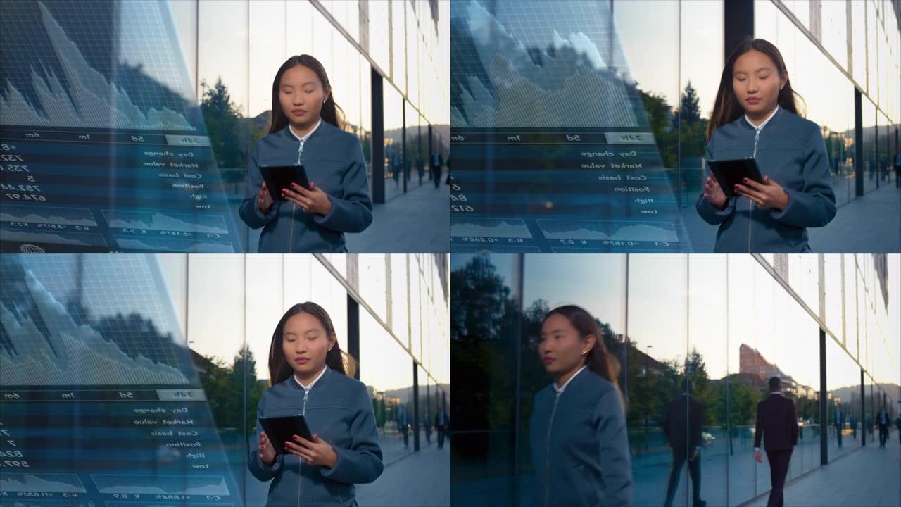 TS年轻的亚洲女企业家在沿着现代商业大楼行走时在数字平板电脑上检查交易应用程序