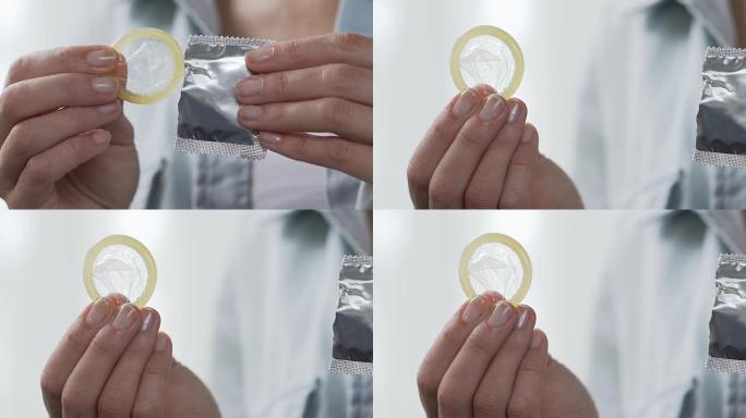 女孩手指从包装中取出避孕套，预防艾滋病，避孕