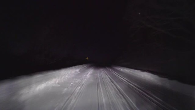 晚上在森林的雪路上开车。