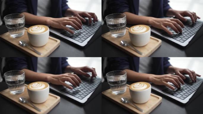 一名妇女在笔记本电脑附近用咖啡和水工作的特写镜头