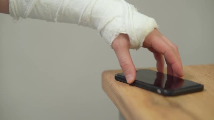 一个在石膏模型中摔断了手的人拿着智能手机。手臂上有石膏的人。