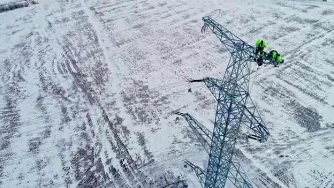 冬季景观中安装电塔的工人的空中倾斜镜头