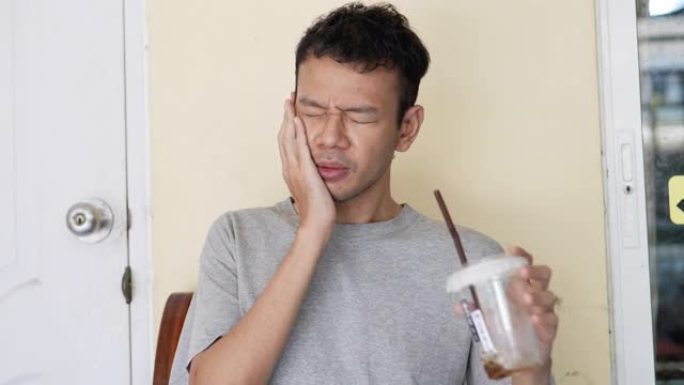 亚洲男子喝咖啡后牙痛
