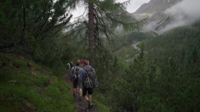 徒步旅行者的队伍在山上游走树木繁茂的小径