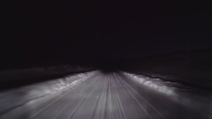 晚上在森林的雪路上开车。