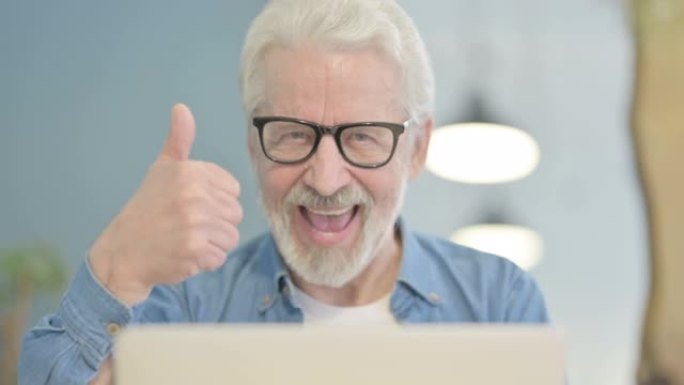 在笔记本电脑上工作的老人竖起大拇指