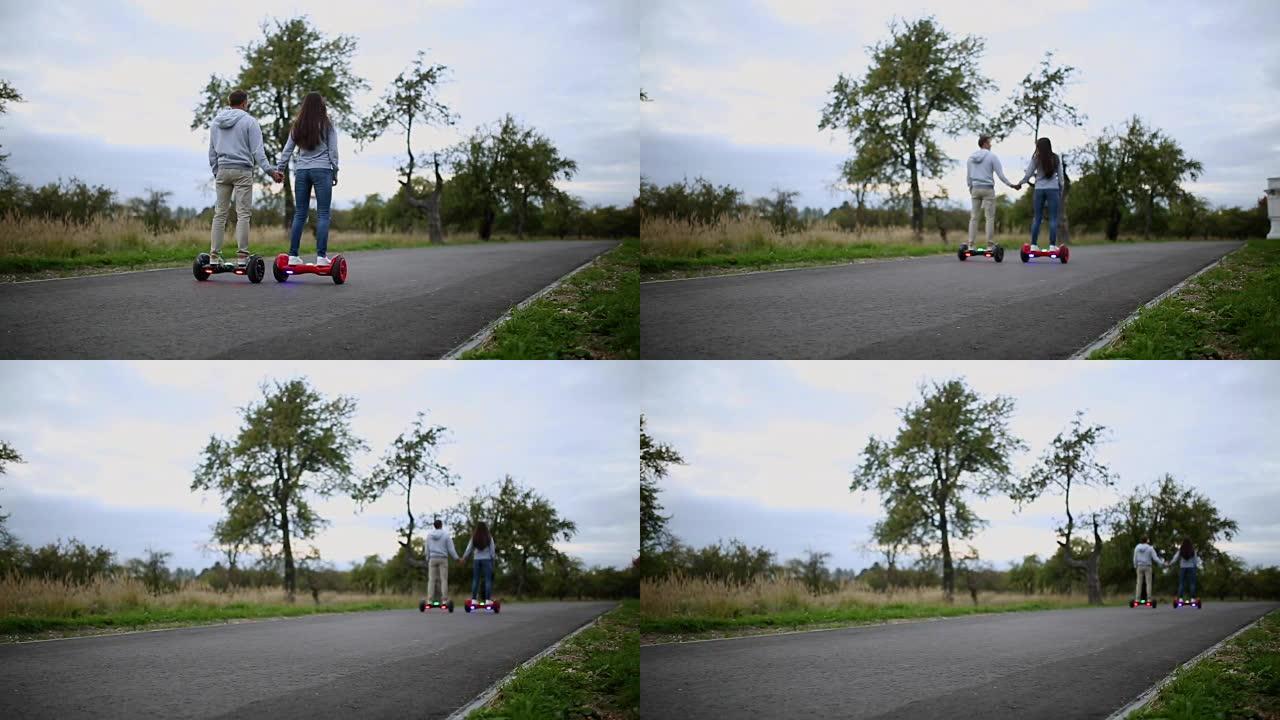 年轻的男人和女人骑在公园的气垫板上。内容技术。一个新的运动。双轮自平衡电动滑板智能特写。户外电动滑板