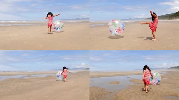 女孩在海滩跑步和踢大球