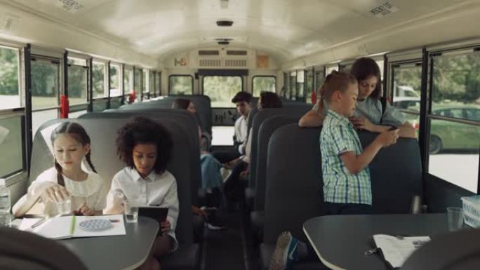 青少年同学坐校车聊天。多元文化课堂聊天玩耍。