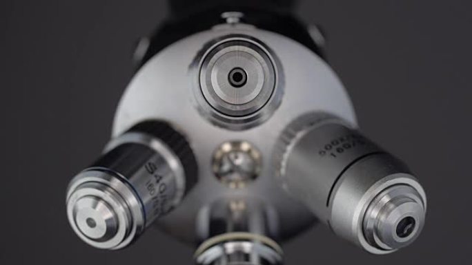 一只手旋转一组显微镜透镜以实现所需的增加