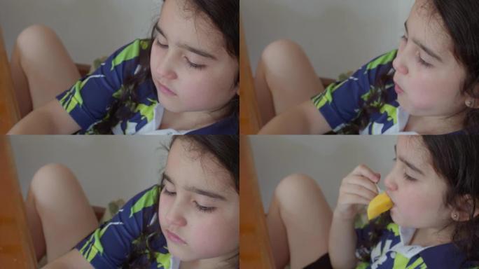 一个女孩坐在桌子旁边吃美味的芒果; 健康饮食概念