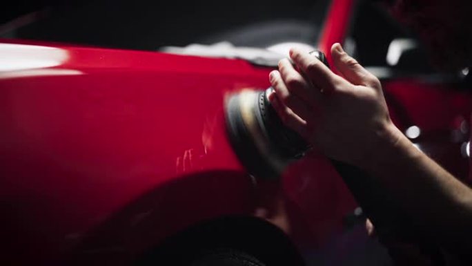 汽车广告风格的镜头专业汽车美容师使用电动抛光机在清洗和细节车辆后在漂亮的红色跑车的挡泥板上工作