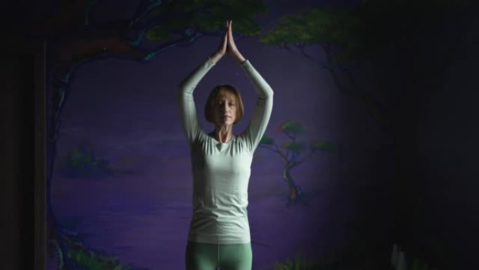 一个女人在紫色的墙壁上练习瑜伽的镜头