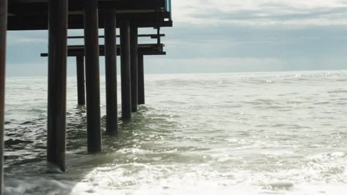柱子，金属码头支撑在海里，从下面看，海浪击中它们。