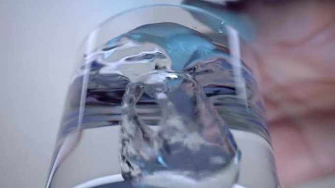 手将钻石倒入装有水的玻璃杯中，形成一丝大气泡