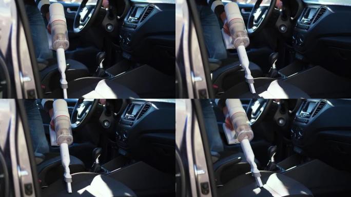 一个男人用吸尘器吸尘汽车座椅的特写镜头。手握着无绳吸尘器，清洁汽车内部。