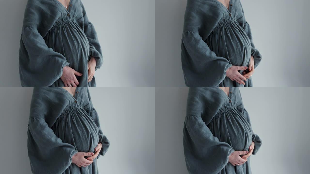 一个孕妇的腹部特写，她的手放在她的腹部。穿着裙子的怀孕女孩。