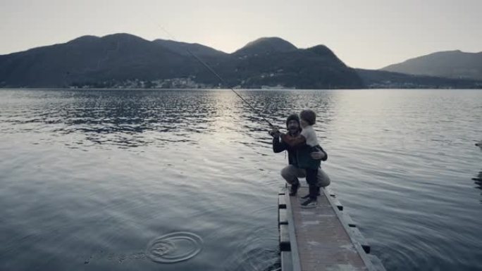 父子俩一起在码头上钓鱼，可以看到后面的湖泊和山脉
