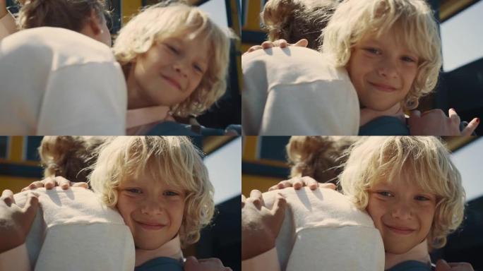 特写学校男孩在黄色公共汽车上拥抱妈妈。小学生向母亲说再见