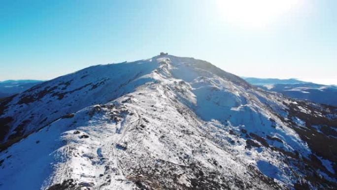 蓝天日白雪覆盖的山脉的空中无人机视图