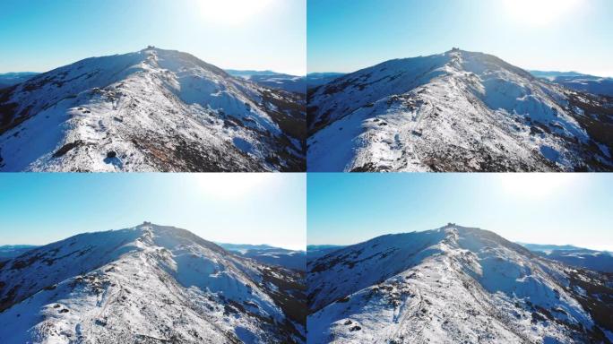 蓝天日白雪覆盖的山脉的空中无人机视图