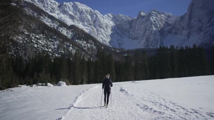 女人在雪地里徒步旅行，远离山线附近的观众