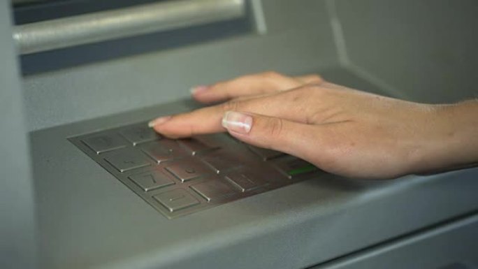 女人输入PIN码以检查银行帐户并从ATM取款