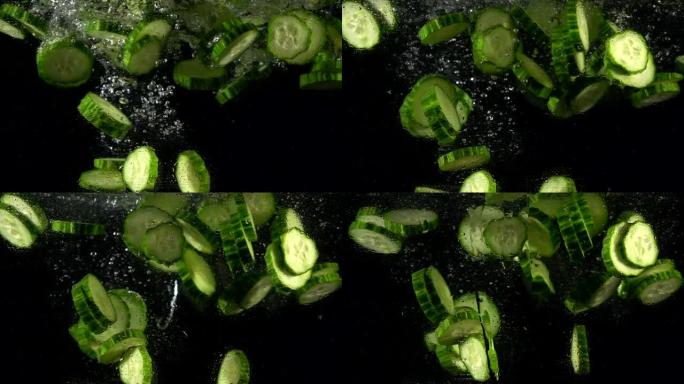 落水新鲜黄瓜片的超慢动作。孤立在黑色背景上。在高速电影摄像机上拍摄，4k 1000fps。