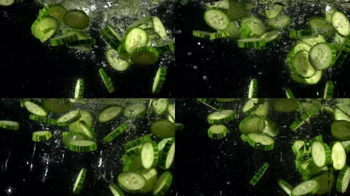 落水新鲜黄瓜片的超慢动作。孤立在黑色背景上。在高速电影摄像机上拍摄，4k 1000fps。